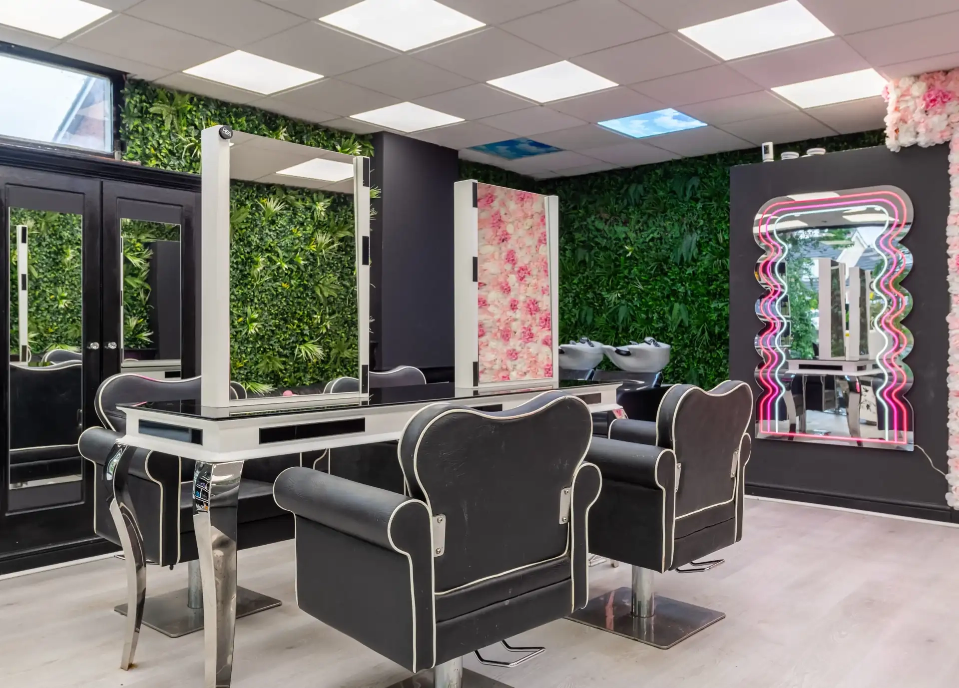 Inside Hallie's Beauty salon — styling stations with green living wall and mirrors